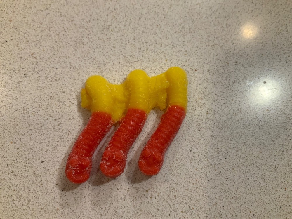 3 gummy worms that are stuck together that are yellow and red